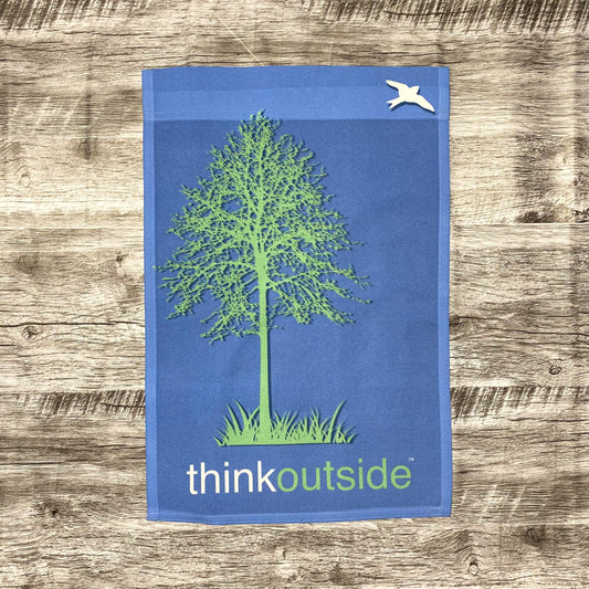 Periwinkle blue garden flag featuring a bright green silhouette of a tall tree and a bird with the phrase Think Outside. 