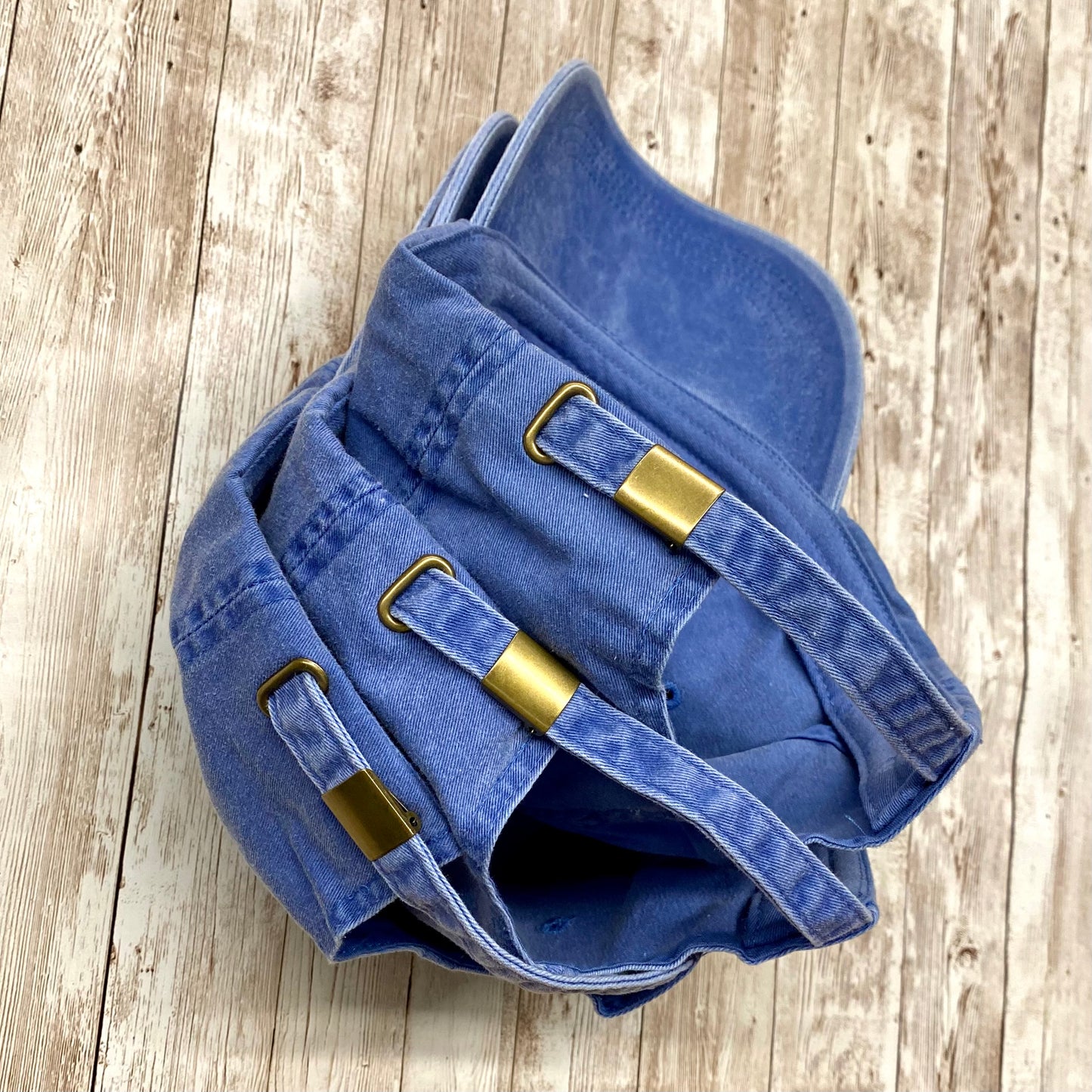 Periwinkle blue garment washed low profile baseball cap with the embroidered silhouette of a tree and bird and the words Think Outside featuring an adjustable brass buckle.