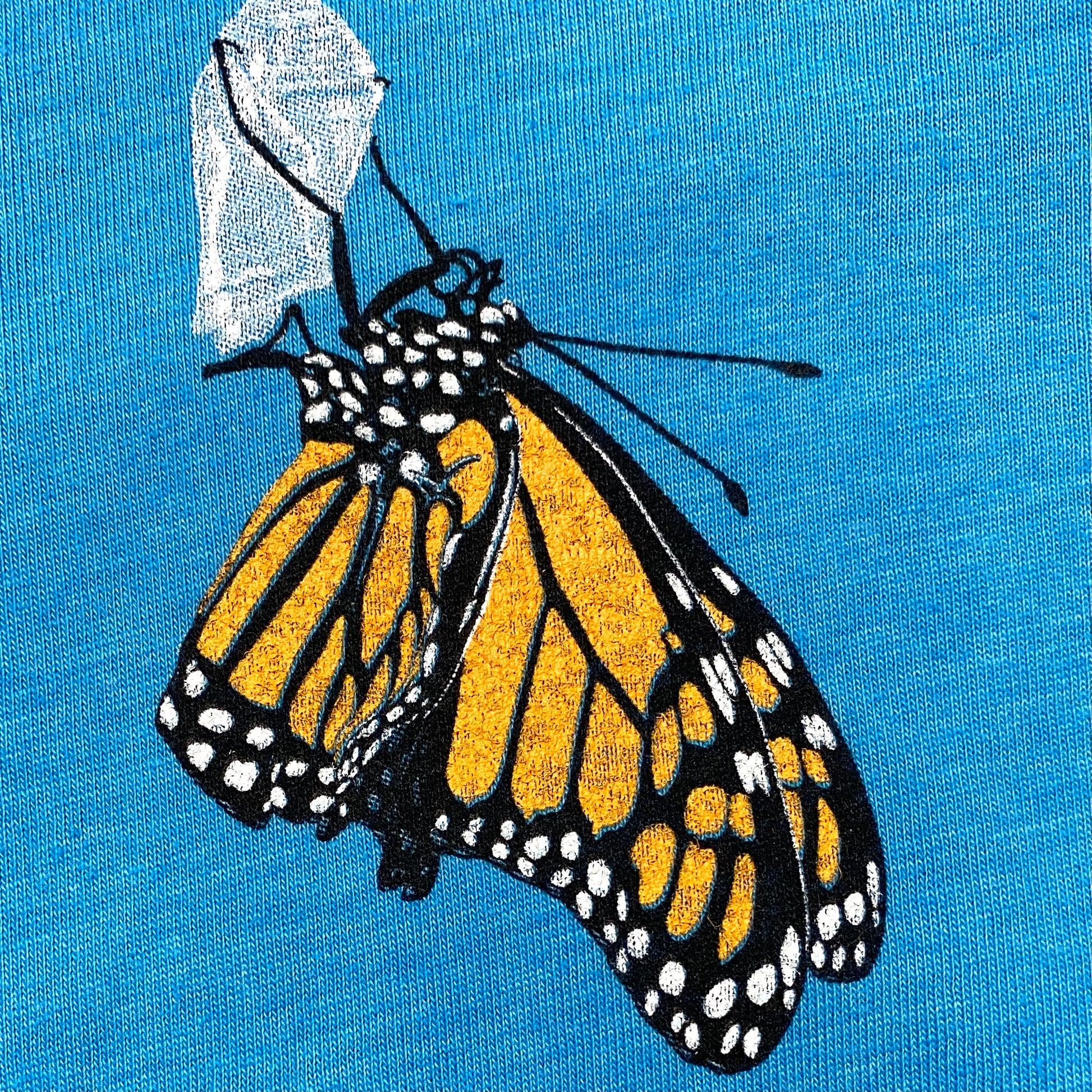 Hand drawn Monarch butterfly on a super soft heather aqua graphic tee. Features the phrase Think Outside.