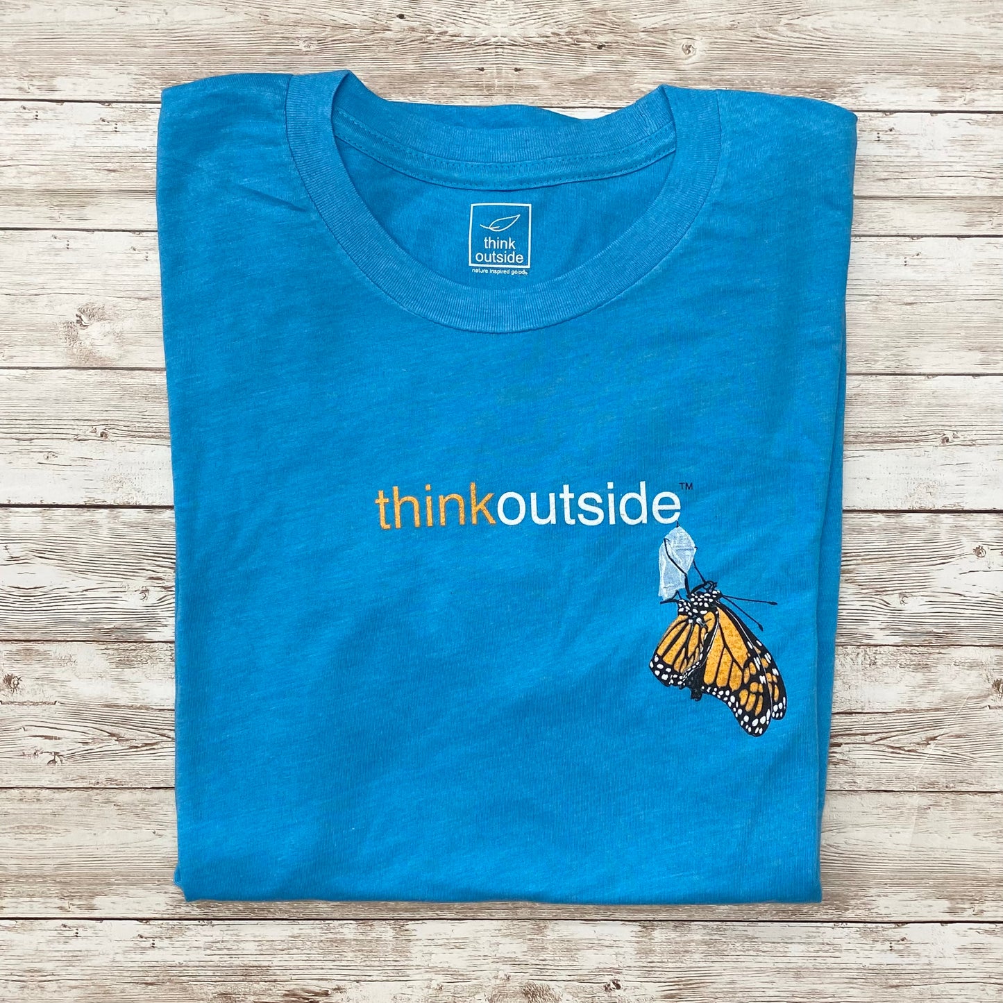 Hand drawn Monarch butterfly on a super soft heather aqua graphic tee. Features the phrase Think Outside.
