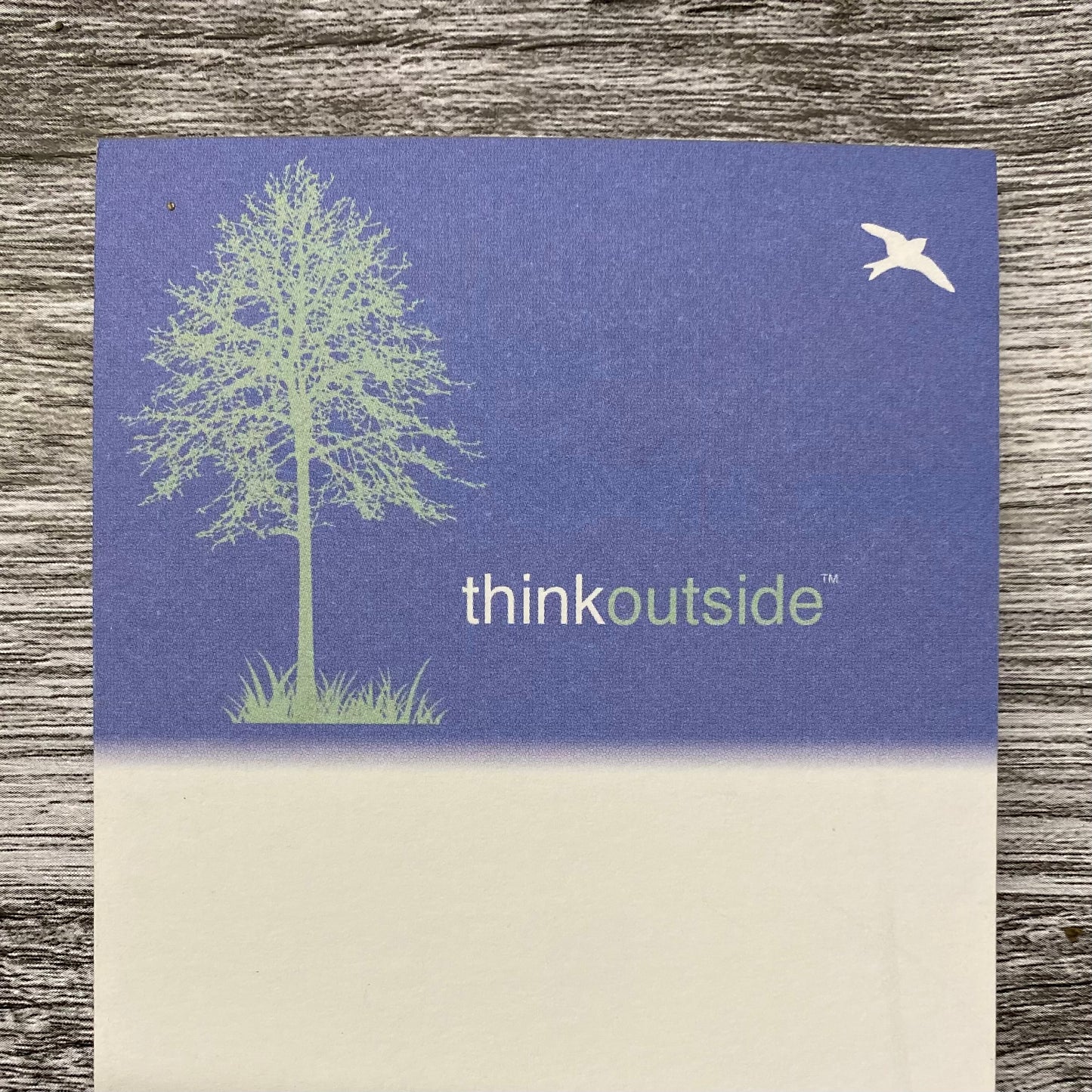 A notepad of 50 sheets of paper featuring a silhouette drawing of a tree and bird. It also includes the phrase Think Outside.